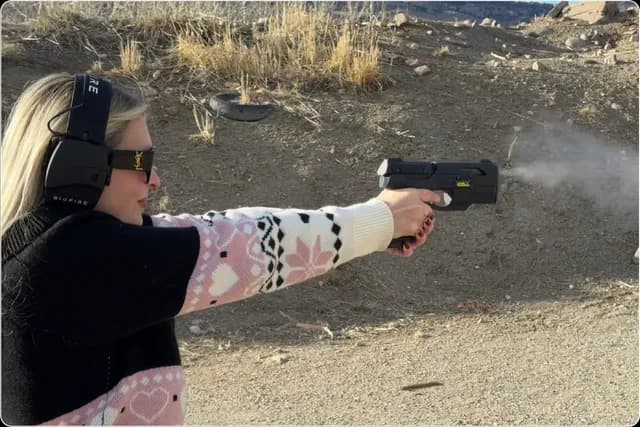 A woman wearing ear protection firing the Smart Gun at an outdoor range.